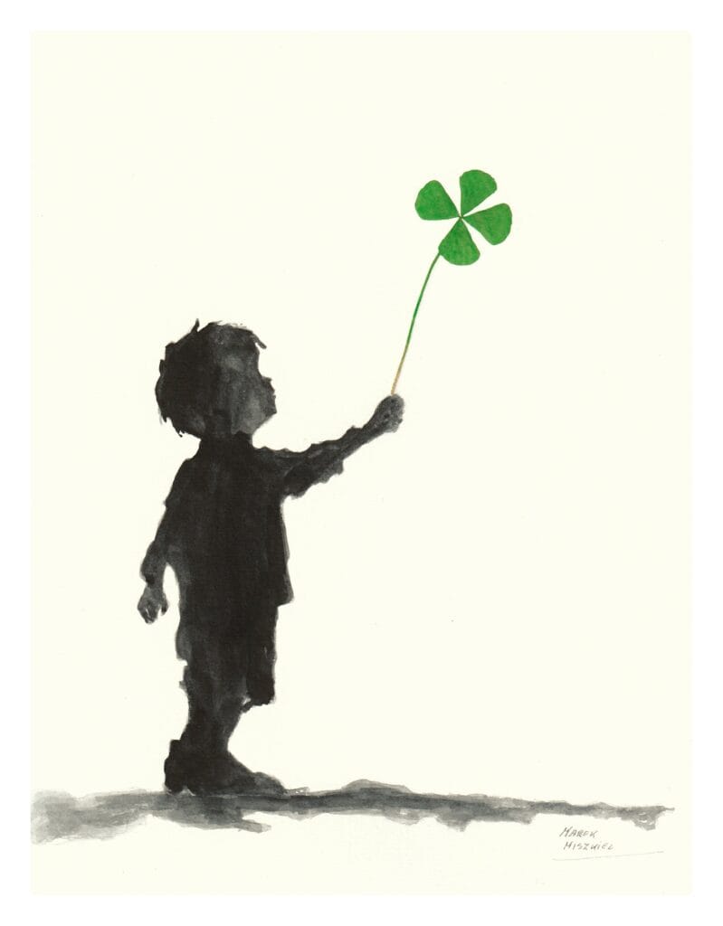 chlopiec trzymajacy w dloni wyciagnieta do gory czterolistna konczyne szczescia